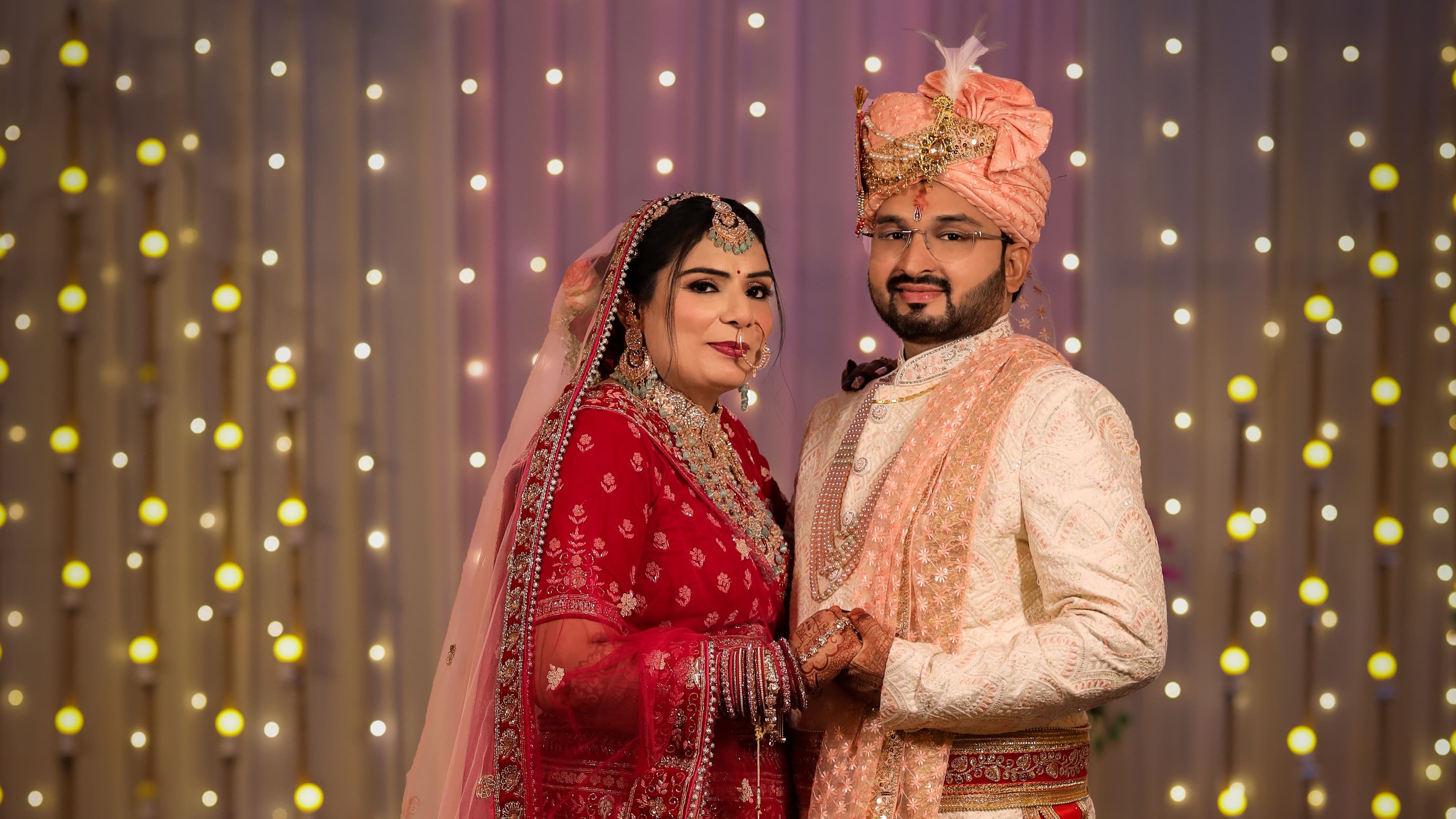 Bride and groom posing together in front of a fairy-light backdrop